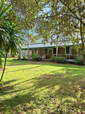 A house with a front porch, a lawn, and a tree in the foreground. - Mera Norfolk Island (Norfolk Island)