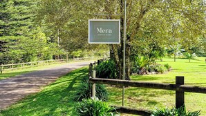 A sign for 'Mera Norfolk Island' with a wooden fence and lush greenery in the background. - Mera Norfolk Island (Norfolk Island)
