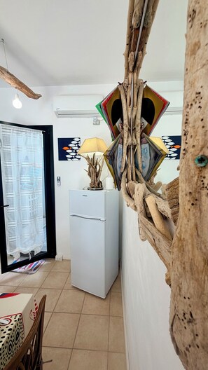 A room with a white refrigerator, a lamp, and a wall decorated with a fish pattern.