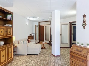 A room with a sofa, a wooden cabinet, a mirror, and patterned flooring. - Balconi sulla Spiaggia by Interhome (Bellano)