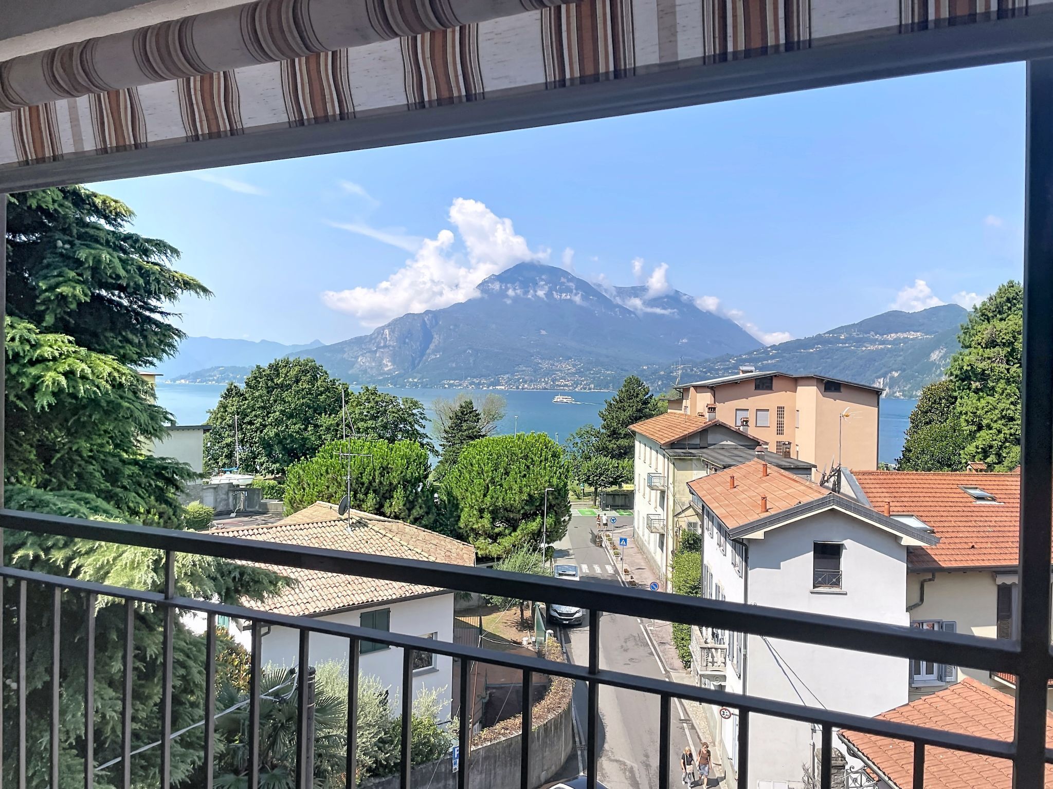 A balcony with a view of a coastal town, a mountain, and a body of water.