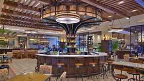Un espace bar doté d’un comptoir central, de plusieurs options d’aménagement pour s’asseoir et d’un plafond décoratif agrémenté de luminaires suspendus.