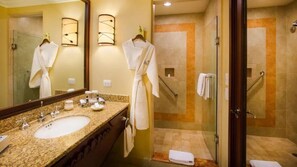Une salle de bain dotée d’un comptoir en granit, de deux lavabos, d’un grand miroir et d’une cabine de douche en verre.
