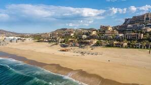 Un complejo turístico frente al mar con villas privadas en la playa, una playa de arena y vistas al océano.