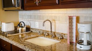 A kitchen with granite countertops, a stainless steel kettle, a coffee maker, and a toaster. - Junior Ocean View Suite with Sunset Views in Cabo (Cabo San Lucas)