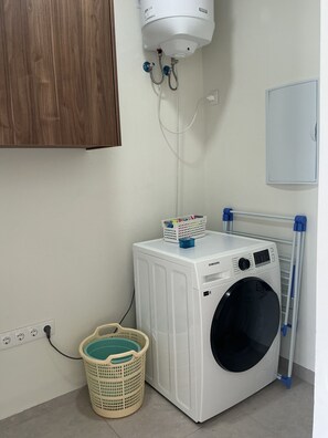 A laundry area with a white washing machine, a drying rack, and a wall-mounted heater. - Nice View Apt 8 - 2-BR apartment with AC on spectacular Mahuma hill (Willemstad)