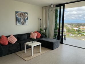 A modern living room with a sofa, a coffee table, and a painting on the wall. - Nice View Apt 8 - 2-BR apartment with AC on spectacular Mahuma hill (Willemstad)