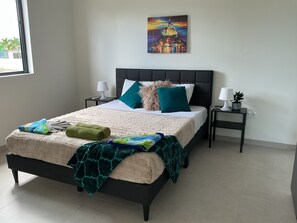 A neatly made bed with a quilt, pillows, and a blanket. There are two bedside tables with lamps and a small potted plant. - Nice View Apt 8 - 2-BR apartment with AC on spectacular Mahuma hill (Willemstad)