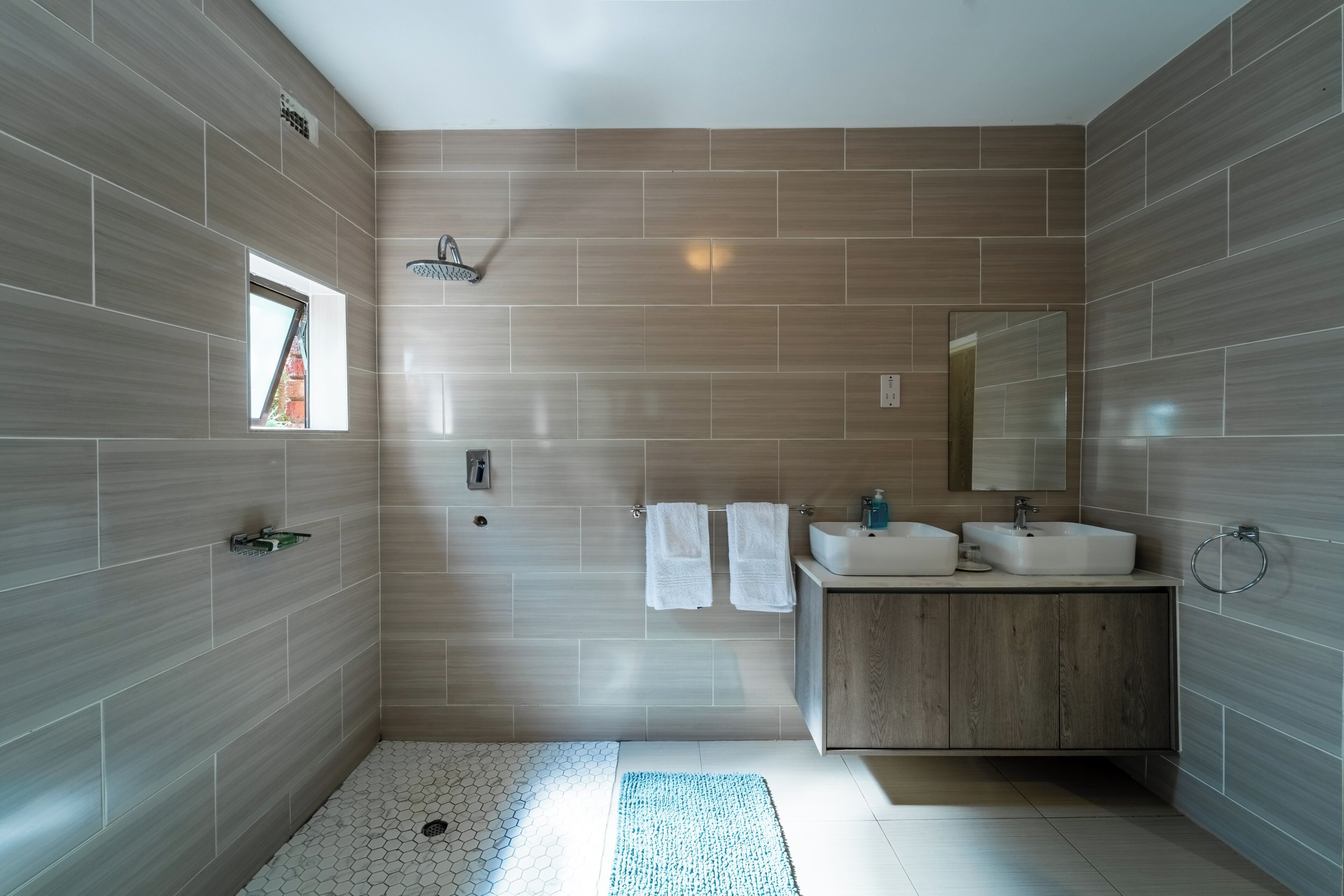 Une salle de bain moderne avec une douche, un lavabo et un miroir.
