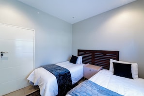 Une chambre avec deux lits, une armoire et une table de chevet.
