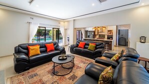 A modern living room with two black leather sofas, a coffee table, and a patterned rug.