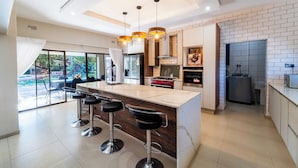 A modern kitchen with a central island, bar stools, and a view to the outside.