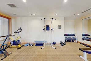 Ein Fitnessraum mit Trainingsgeräten, einer Spiegelwand und einer Hantelbank.