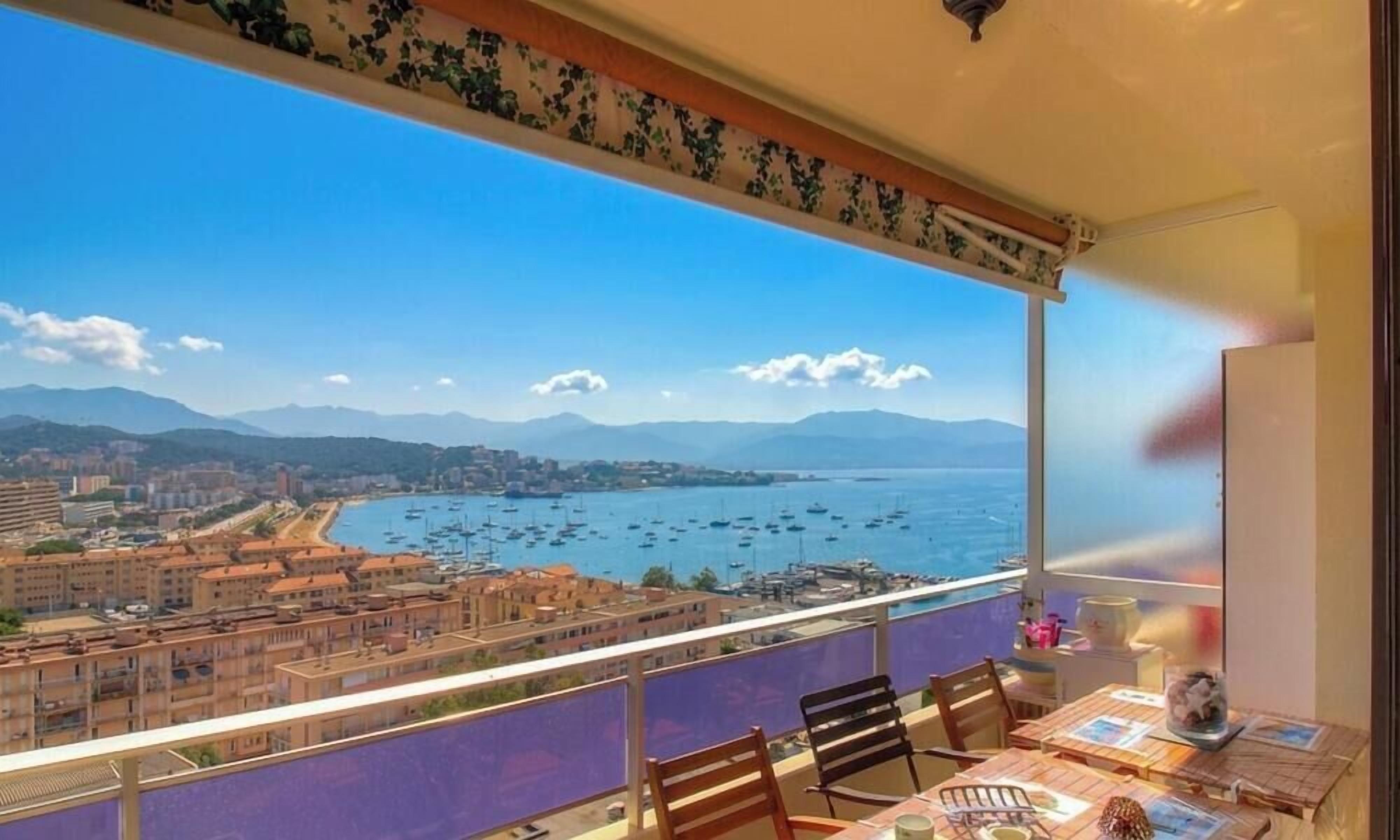 Ein Balkon mit Blick auf eine Küstenstadt und das Meer.