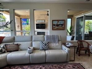 A living room with a beige sofa, a patterned rug, a television, and a painting on the wall. - Relaxing getaway next to award winning golf course (Nipomo)