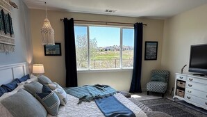 A bedroom with a bed, a television, a dresser, and a window with a view of the outdoors. - Relaxing getaway next to award winning golf course (Nipomo)