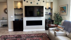 A living room with a flat-screen TV mounted on the wall, surrounded by decorative star-shaped wall hangings. - Relaxing getaway next to award winning golf course (Nipomo)
