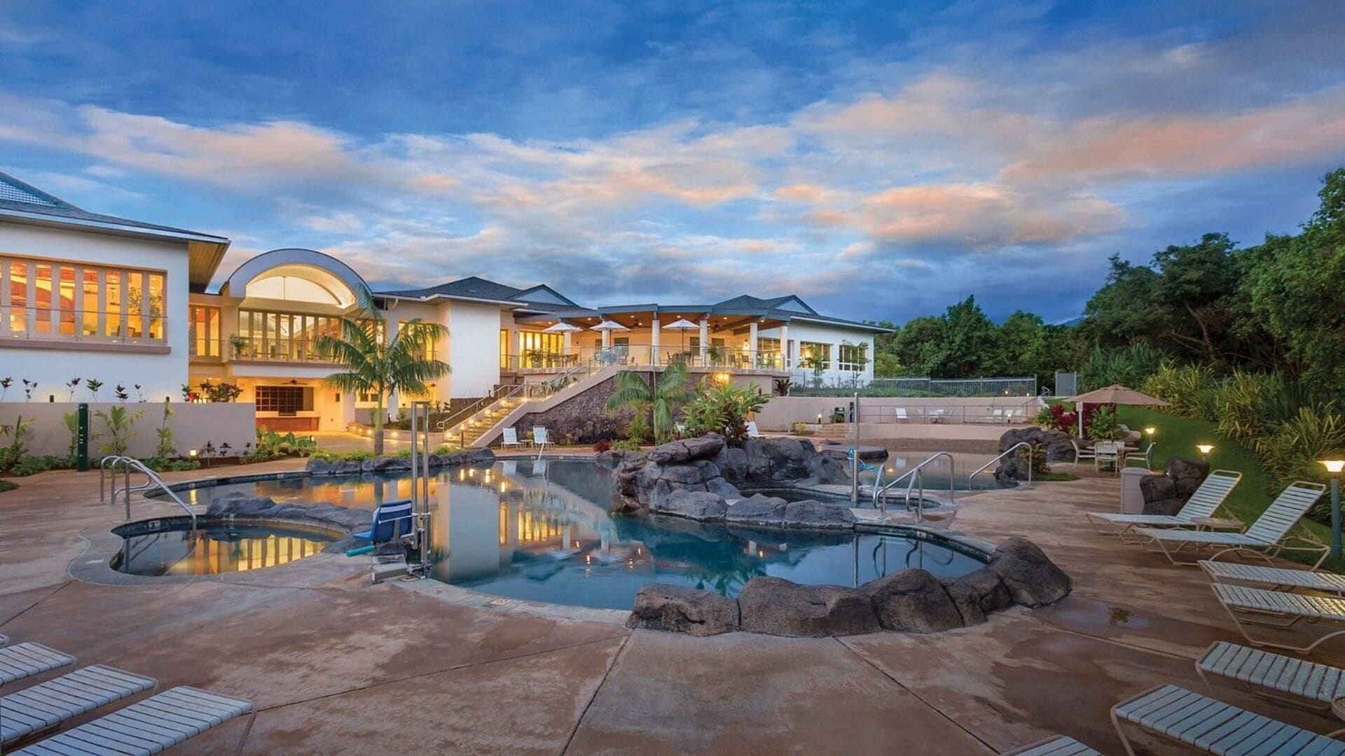 A resort with a pool area, lounge chairs, and a building with multiple levels and outdoor seating.