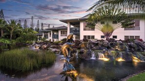 Ein Resort mit Teich, Wasserfall und Delfin-Skulpturen.