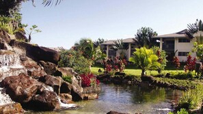 Ein Hotel mit Pool, umgeben von tropischer Vegetation und einem Wasserfall.