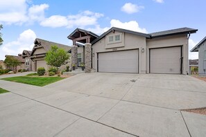 A residential driveway leading to a house with two garage doors, a stone pillar, and a well-maintained lawn. - Lux Retreat Family-Friendly Near USAFA, Parks (Colorado Springs)