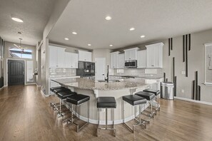 A modern kitchen with a central island, bar stools, and built-in appliances. - Lux Retreat Family-Friendly Near USAFA, Parks (Colorado Springs)