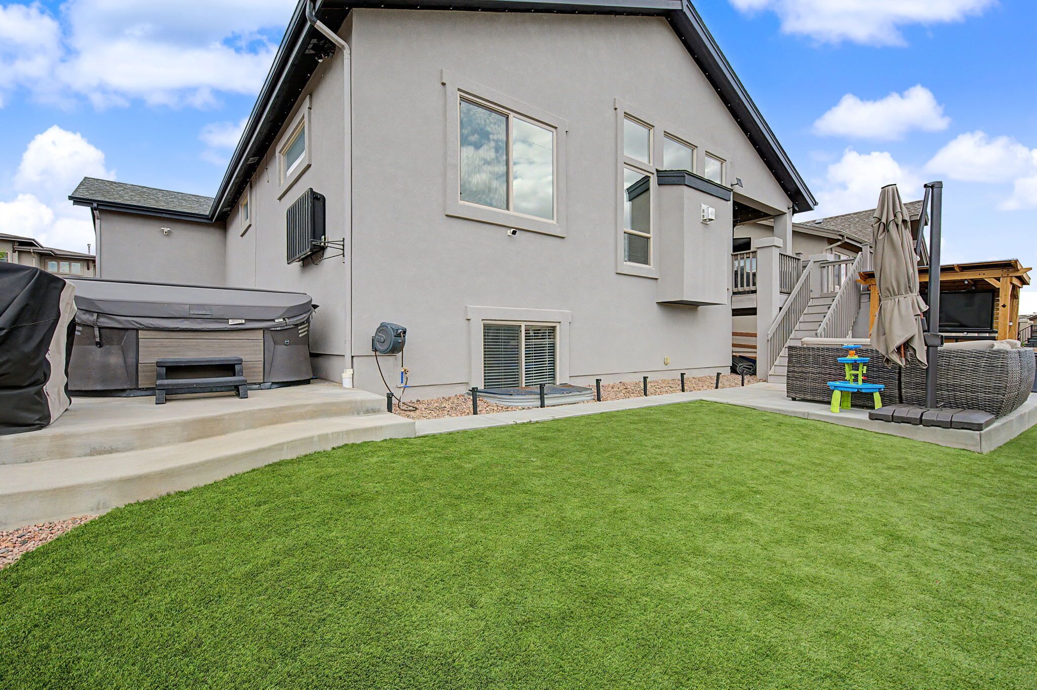 A modern two-story house with a well-maintained lawn, a covered patio area, and a small playset.