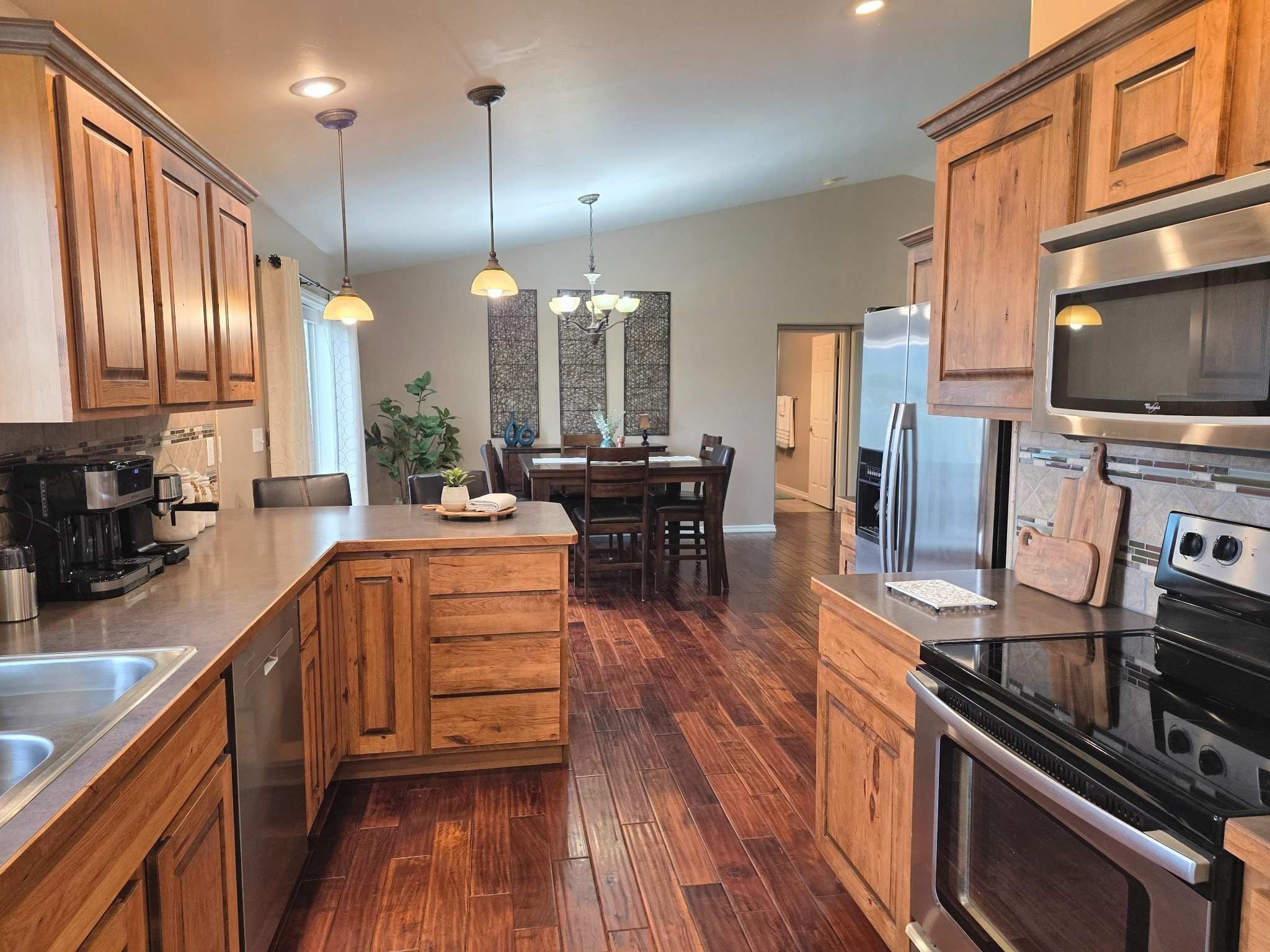 Cocina moderna con armarios de madera, electrodomésticos de acero inoxidable y una isla central.