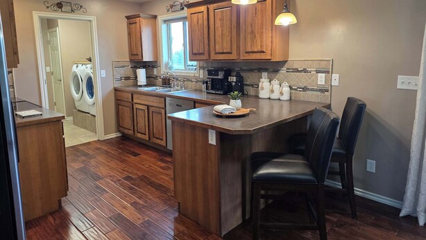 Cocina con armarios de madera, una isla integrada, lavadora y cafetera.