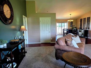 A living room with a brown leather sofa, a round coffee table, a wall clock, and a lamp. - New Listing - Crested Wheat 3 Bedroom Retreat (East Helena)