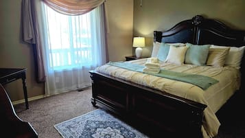 Un dormitorio con cama, mesita de noche, lámpara, ventana con cortinas y alfombra estampada.