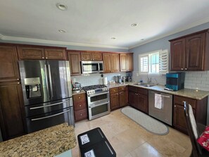 Una cocina con armarios de madera, electrodomésticos de acero inoxidable, encimera de granito y salpicadero de azulejos.