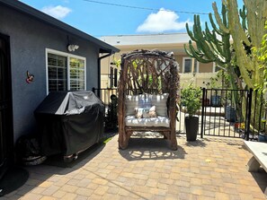 A patio with a covered grill, a cushioned seating area under a wooden arbor, and a large cactus plant. - Casa Pura Vida. 2BED/1BATH Coziest House, Walk to Pacific Beach & Mission Bay. (San Diego)