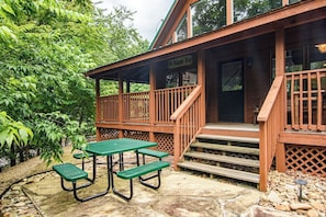 A wooden cabin with a porch, a picnic table, and a sign that reads 'Oh Happy Day.'