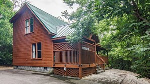 A wooden cabin with a metal roof, a wooden deck, and a stone foundation. - Private Peaceful Cabin Near Dollywood w/ Hot Tub (Sevierville)