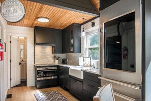 Una cocina moderna con armarios oscuros, electrodomésticos de acero inoxidable y techo de madera.