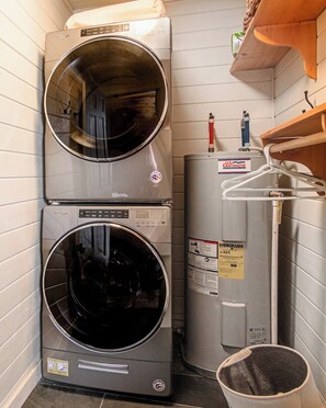 Un área de lavandería con dos lavadoras Whirlpool apiladas y un calentador de agua.