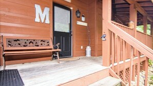 A wooden building with a large 'M' sign, a bench, and a welcome sign. - Private Peaceful Cabin Near Dollywood w/ Hot Tub (Sevierville)