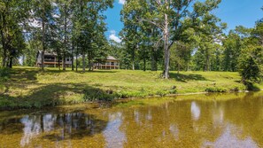 A lakeside property with a cabin and a guesthouse, surrounded by trees and a clear sky. - Lux Waterfront Cabin - 2 King Ensuites, Large Covered Porch, Kayaks, Fire Pit! (Royal)