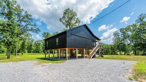 A black barn with a wooden staircase leading up to a covered porch.