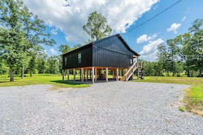 A black barn with a wooden staircase leading up to a covered porch.