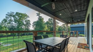 An outdoor patio with a table and chairs, overlooking a fenced yard with trees.