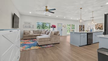 A spacious living area with a sofa, a coffee table, and a kitchen area with a dishwasher.