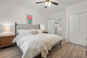 A bedroom with a bed, nightstands, a ceiling fan, a door, and a wardrobe. - Lux Waterfront Cabin - 2 King Ensuites, Large Covered Porch, Kayaks, Fire Pit! (Royal)