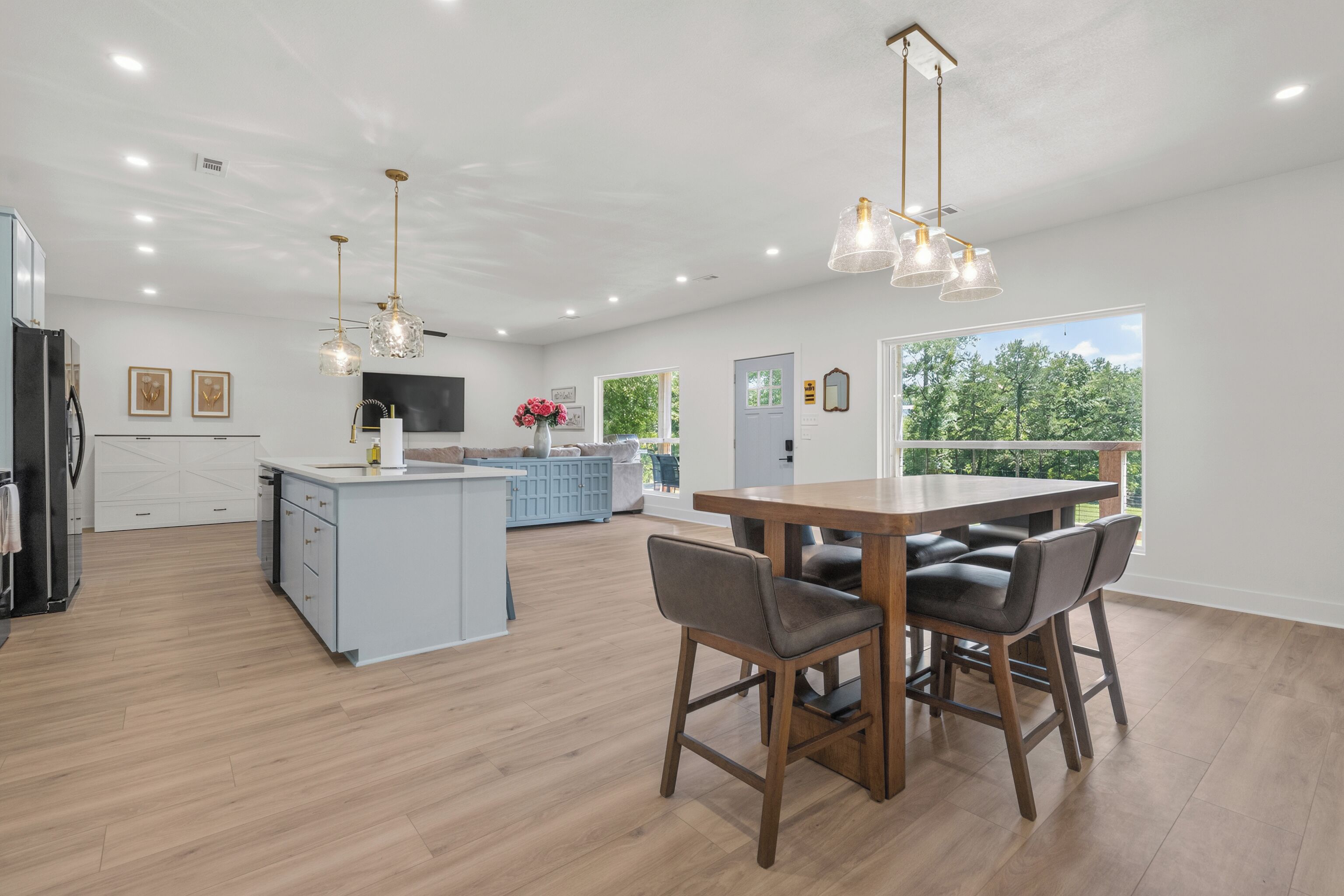 A spacious kitchen with a central island, wooden dining table, and chairs.