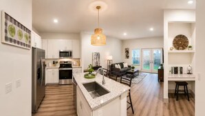 Una cocina moderna con armarios blancos, electrodomésticos de acero inoxidable y una isla central con fregadero.