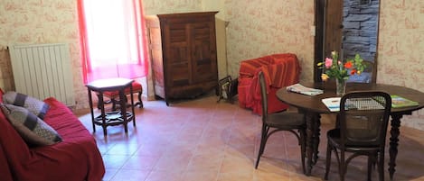 Un salon chaleureux avec un canapé, une petite table, un meuble en bois et un coin repas comprenant une table et des chaises.