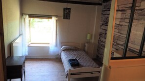 A small, single-bed room with a window, a bedside table with a lamp, and a radiator. - La Bergerie de Louisa (sleeps 4–5) (MARVEJOLS)