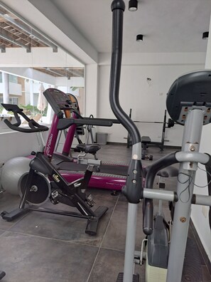 Ein Fitnessraum mit Cardiogeräten, einer Hantelbank und Trainingsbällen.