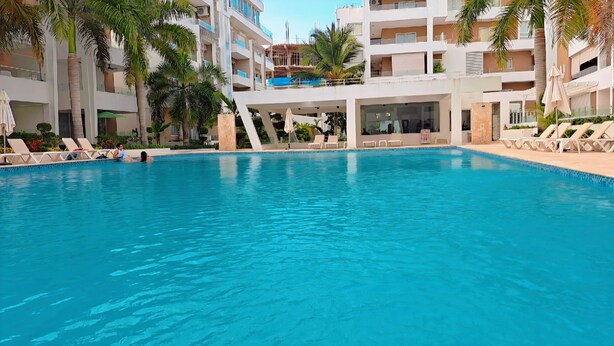 A pool area with lounge chairs and palm trees. - COSTA DE LUXE (Bayahíbe)